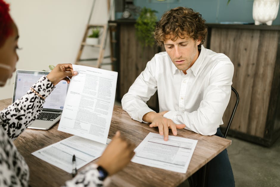 Two professionals reviewing documents in an office setting, focused on analytical tasks.
