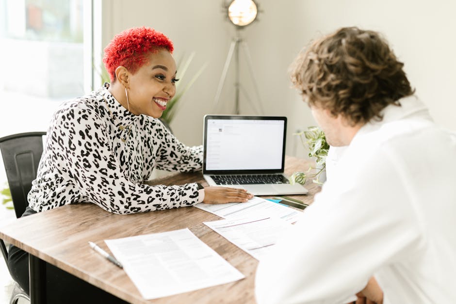 Smiling professionals discussing business documents at modern office table.